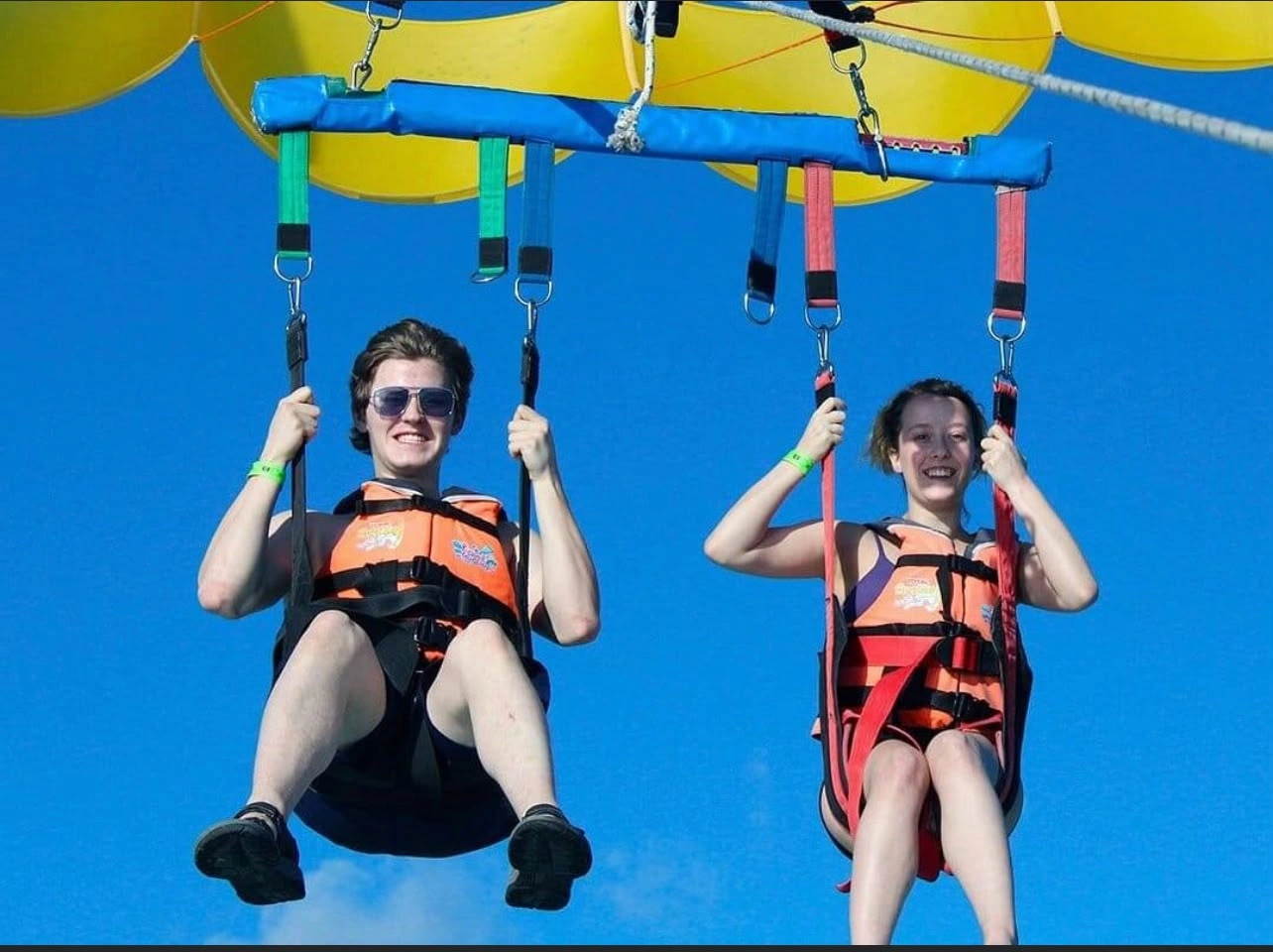 Dos participantes con chalecos y arneses durante un vuelo de parasailing